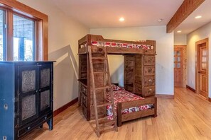 A bunk bed with a ladder, a cabinet with decorative panels, and a wooden door. - Two Bears | Mountain Views and Game Nights (Franklin)