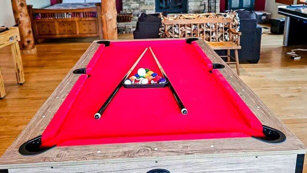 Ein Billardtisch mit roter Spielbahn und einem Queue in der Mitte.