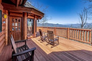 A wooden deck with a bench and two rocking chairs, overlooking a mountainous landscape. - Two Bears | Mountain Views and Game Nights (Franklin)