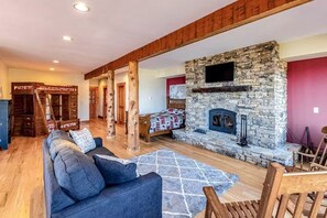 A cozy living room with a stone fireplace, wooden beams, and a sofa. - Two Bears | Mountain Views and Game Nights (Franklin)