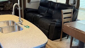 Ein kompaktes Wohnmobil-Interieur mit einer Küchenzeile, einer Sitzecke und einem Fenster.