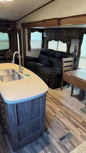 Een compact camperinterieur met een kitchenette, een zithoek en een raam.