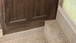 Eine große Holzkabine mit zwei Türen und einer Schublade, an einer Wand mit einem Fenster platziert.