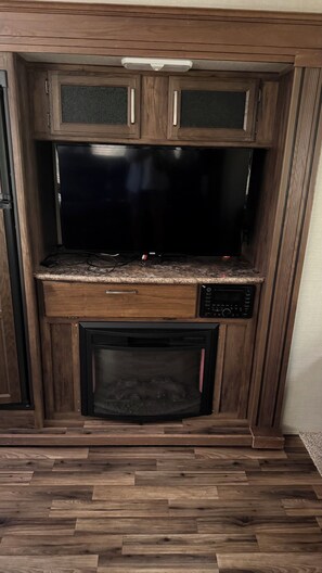 Een keuken met een magnetron, een fornuis en een grote flatscreen-televisie.