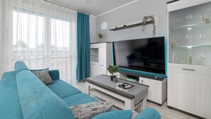 Ein modernes Wohnzimmer mit einer Couch, einem Couchtisch, einem Fernseher und einer Vitrine mit Dekoration.