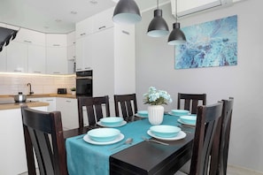 Un espace repas moderne avec une table dressée pour six personnes, entourée de chaises en bois.