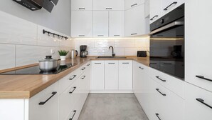 Eine moderne Küche mit weißen Schränken, einer Holz Arbeitsplatte, einem eingebauten Backofen und einer schwarzen Dunstabzugshaube.