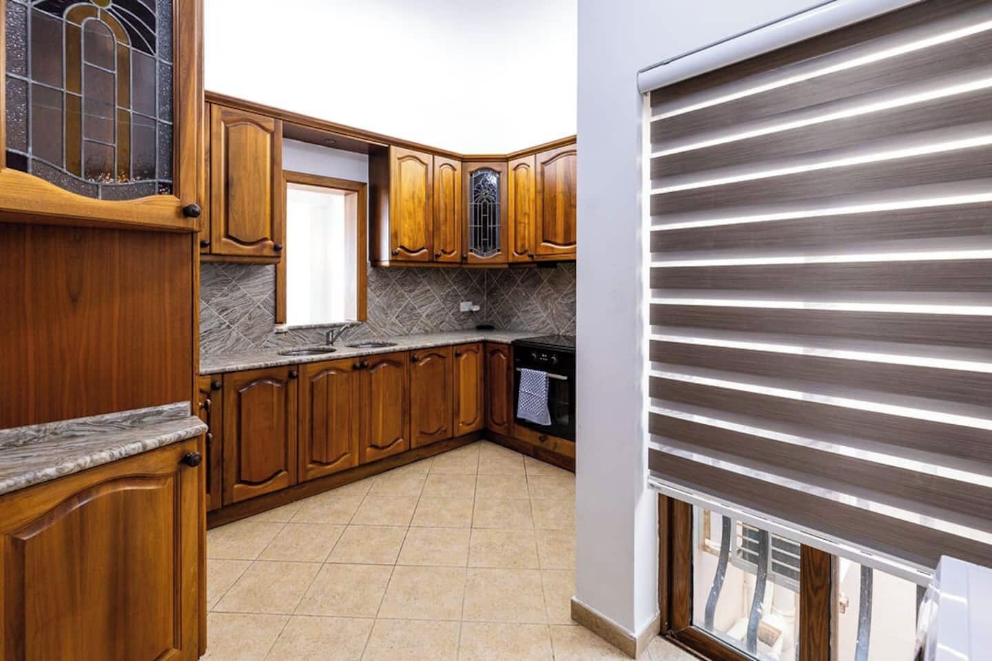 A kitchen with wooden cabinets, a marble countertop, and a built-in oven.