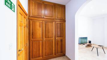 Ein Zimmer mit einem Holzschrank, einem Brandschutzschild, einem Fernseher und einem kleinen Tisch.