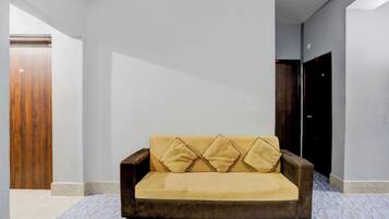 Een moderne woonkamer met een bank, een houten deur en een donkerdrijende garderobe.