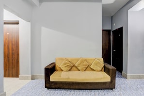 A modern living room with a sofa, a wooden door, and a dark-colored wardrobe.