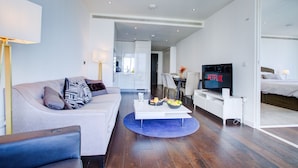 Een moderne woonkamer met een bank, salontafel en een televisie waarop 'NETFLIX' wordt weergegeven.
