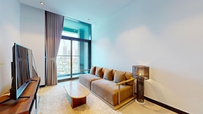 A modern living room with a sofa, a coffee table, a TV, and a floor lamp. - Sleek 1 Bed with Burj Khalifa View l Business Bay (Business Bay)