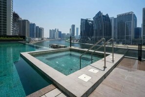 A rooftop pool with a cityscape view, surrounded by high-rise buildings. - Sleek 1 Bed with Burj Khalifa View l Business Bay (Business Bay)