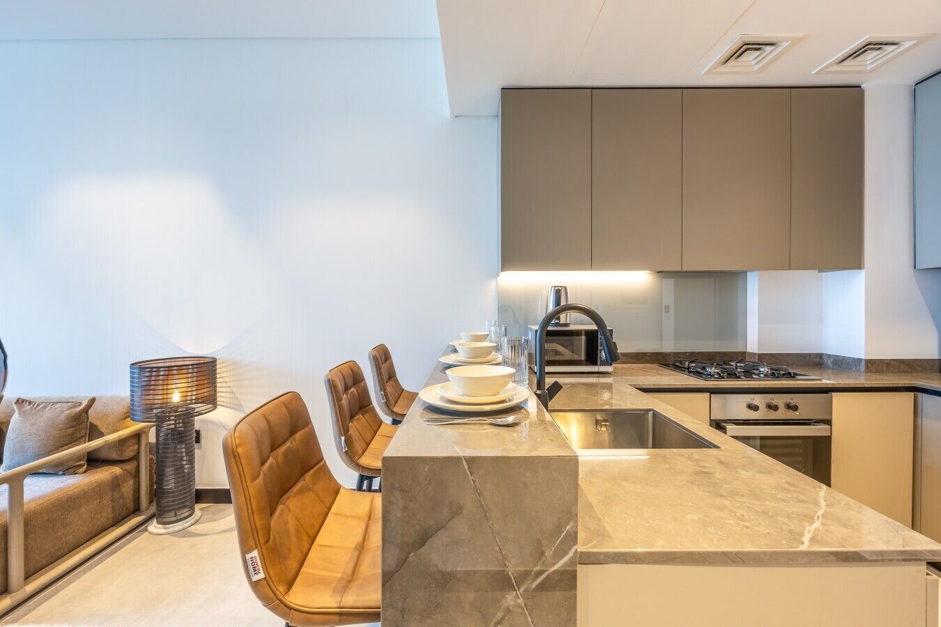 A modern kitchen with a central island, built-in appliances, and a dining area with leather chairs.
