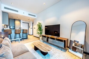 A modern living room with a sofa, a coffee table, a TV, and a large mirror. - Sleek 1 Bed with Burj Khalifa View l Business Bay (Business Bay)