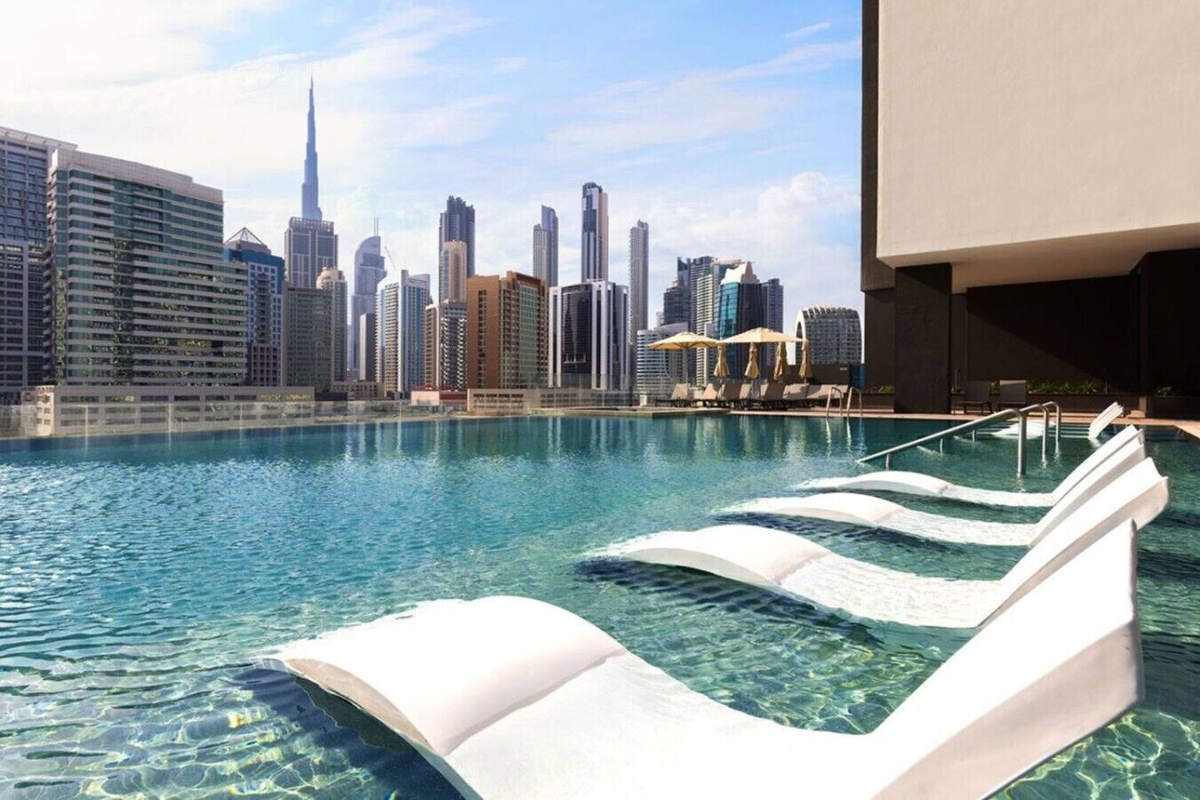 A swimming pool with clear water and a city skyline in the background.