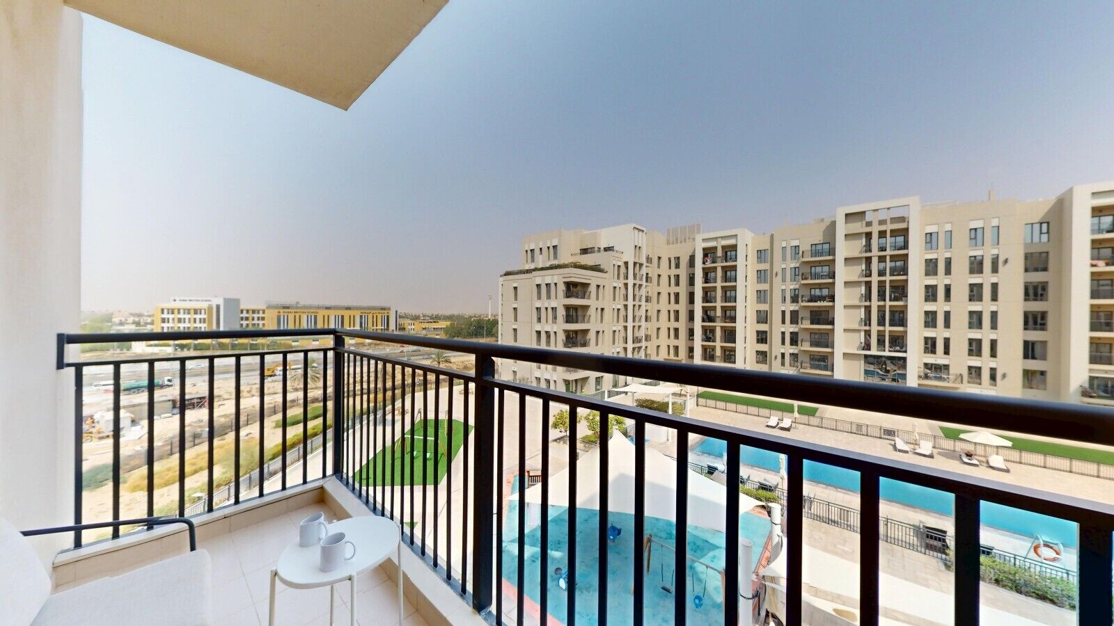 A balcony with a view of a swimming pool and adjacent buildings.