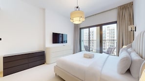 Ein modernes Hotelzimmer mit einem großen Bett, einem Flachbildfernseher, einem Nachttisch und Blick auf die Stadt vom Balkon aus.