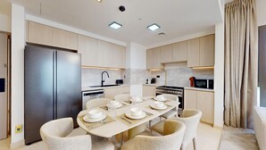 A modern kitchen with a dining area, stainless steel appliances, and light wood cabinetry. - Aesthetic 2 Bed in Townsquare l Pool and Gym (Town Square)