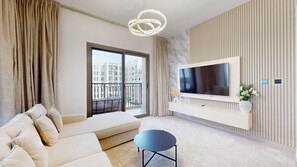 A modern living room with a sofa, a TV mounted on a wall, and a balcony with a view of buildings. - Aesthetic 2 Bed in Townsquare l Pool and Gym (Town Square)