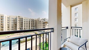 A balcony with a view of a residential building complex, a pool, and a green area. - Aesthetic 2 Bed in Townsquare l Pool and Gym (Town Square)