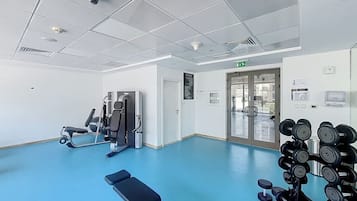 A gym with exercise equipment, a blue floor, and a glass door leading outside.