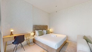 A hotel room with a bed, bedside table, lamp, chair, and a desk with a lamp. - Chic Studio with Canal View l Business Bay (Business Bay)