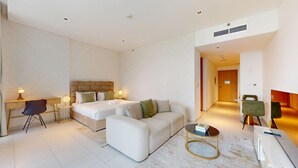 Ein Hotelzimmer mit einem Bett, zwei Nachttischen, einem Sofa, einem Couchtisch und einem Schreibtisch.