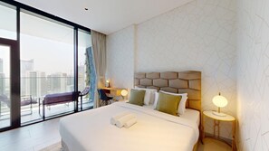 A modern hotel room with a large bed, a desk, and a view of the city through floor-to-ceiling windows. - Chic Studio with Canal View l Business Bay (Business Bay)