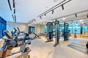 Et fitnesscenter med løbebånd, træningsmaskiner og spejle.