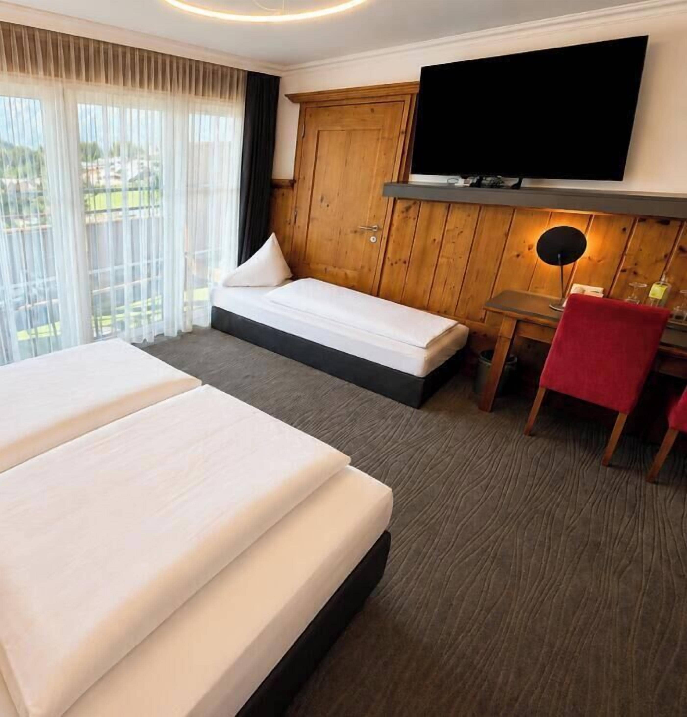 Habitación de hotel con dos camas, un televisor, un escritorio y una silla.