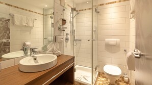 Une salle de bain moderne avec une douche à parois de verre, un lavabo avec un miroir et des toilettes.