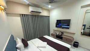 Una habitación de hotel moderna con una cama grande, un televisor de pantalla plana, un escritorio con una silla y un espejo.