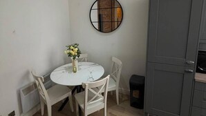 Ein kompakter Wohnraum mit Essbereich, einem grauen Schrank und einem runden Spiegel an der Wand.