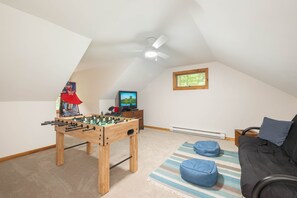 A room with a foosball table, a television, a window, and a ceiling fan. - FirePit, Hot Tub, Dock + Lake "Get Your Creek On" (Swanton)