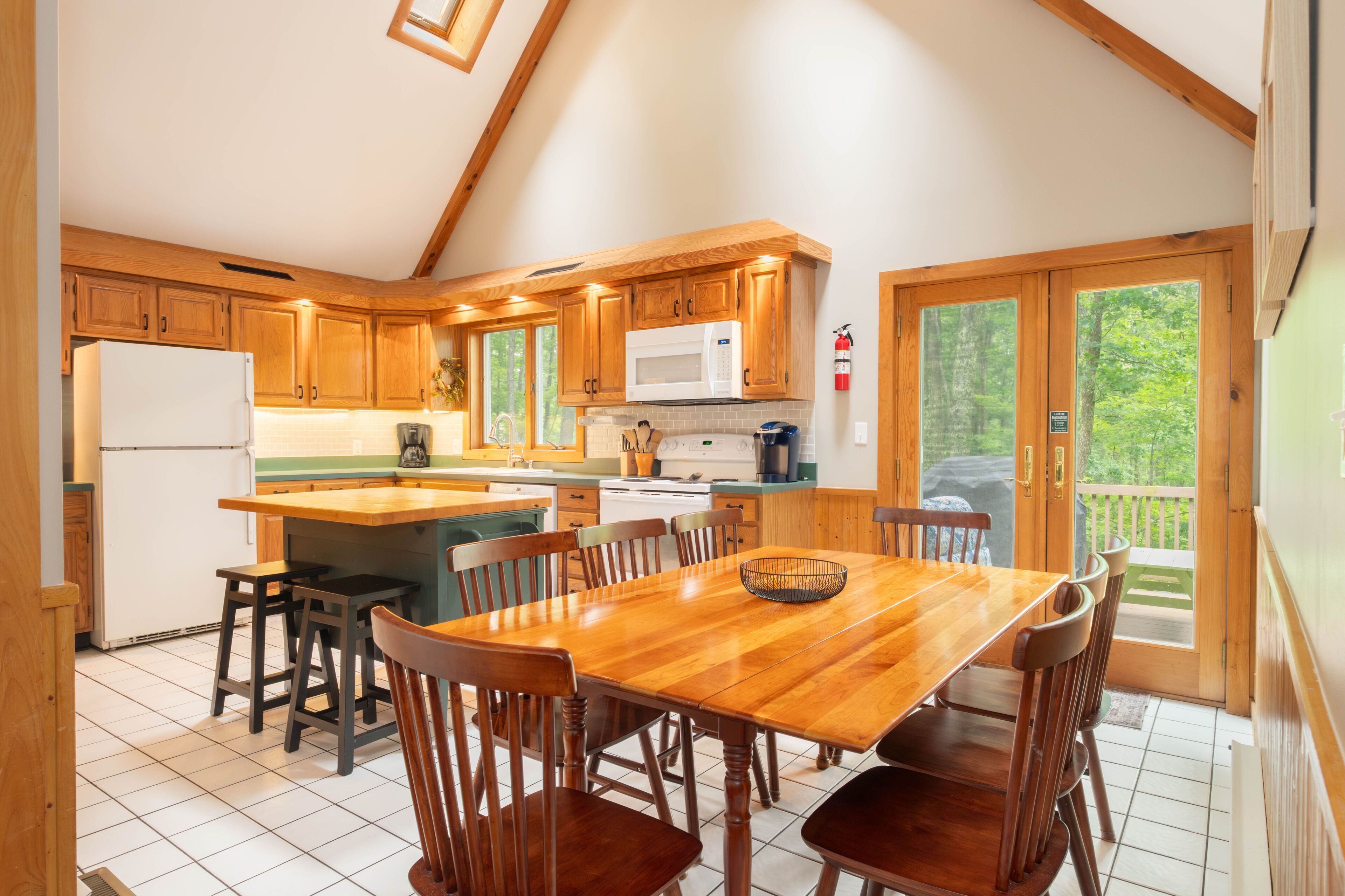 Una cocina con armarios de madera, un microondas y un comedor con mesa y sillas.
