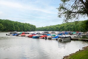 A marina with boats docked along the shore, surrounded by a forested area. - FirePit, Hot Tub, Dock + Lake "Get Your Creek On" (Swanton)