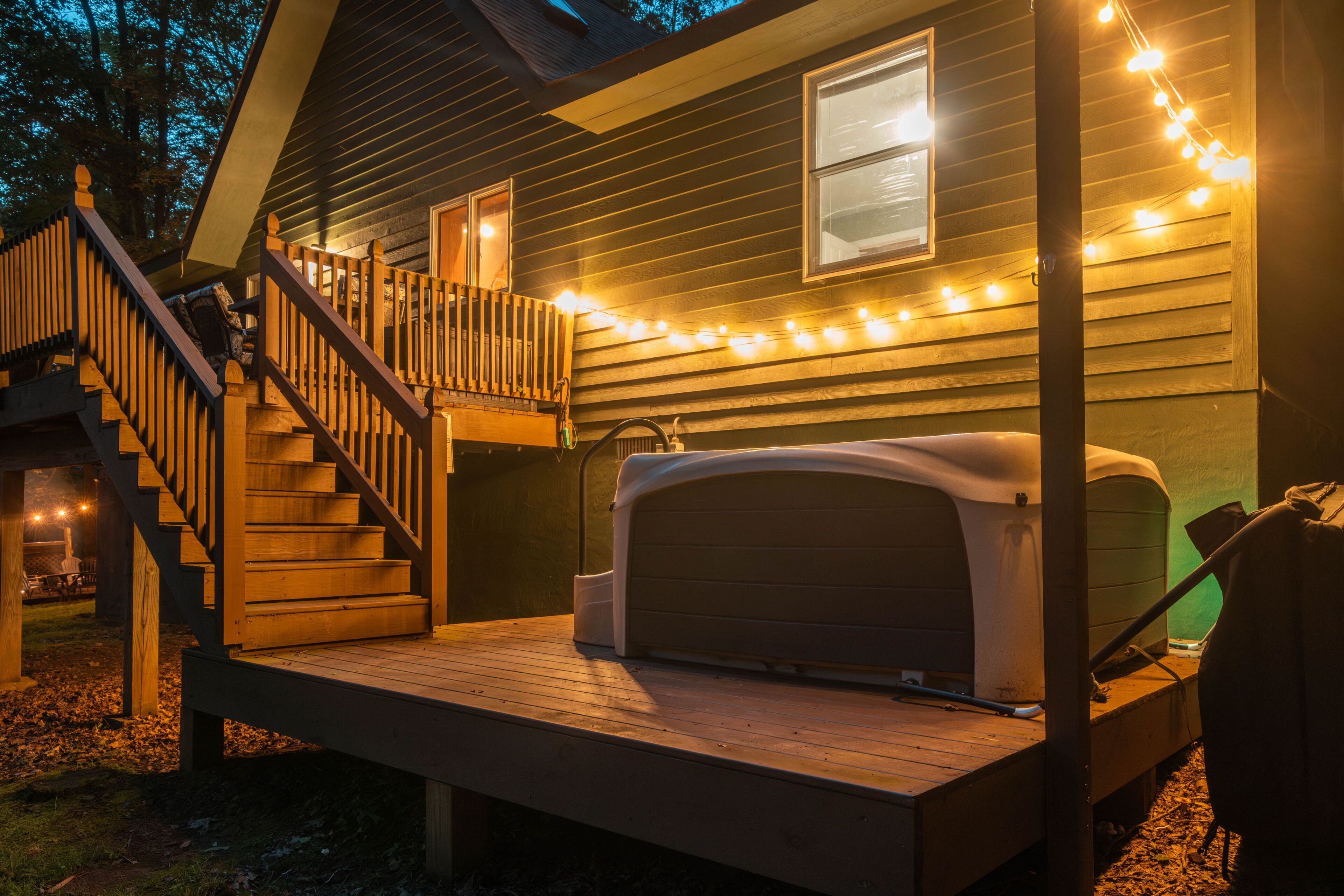 Een huis met een houten terras, een overdekte veranda en lichtjes.