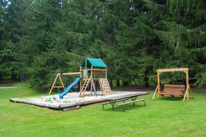 Ein Spielplatz mit Rutsche, Kletterwand und Schaukeln.