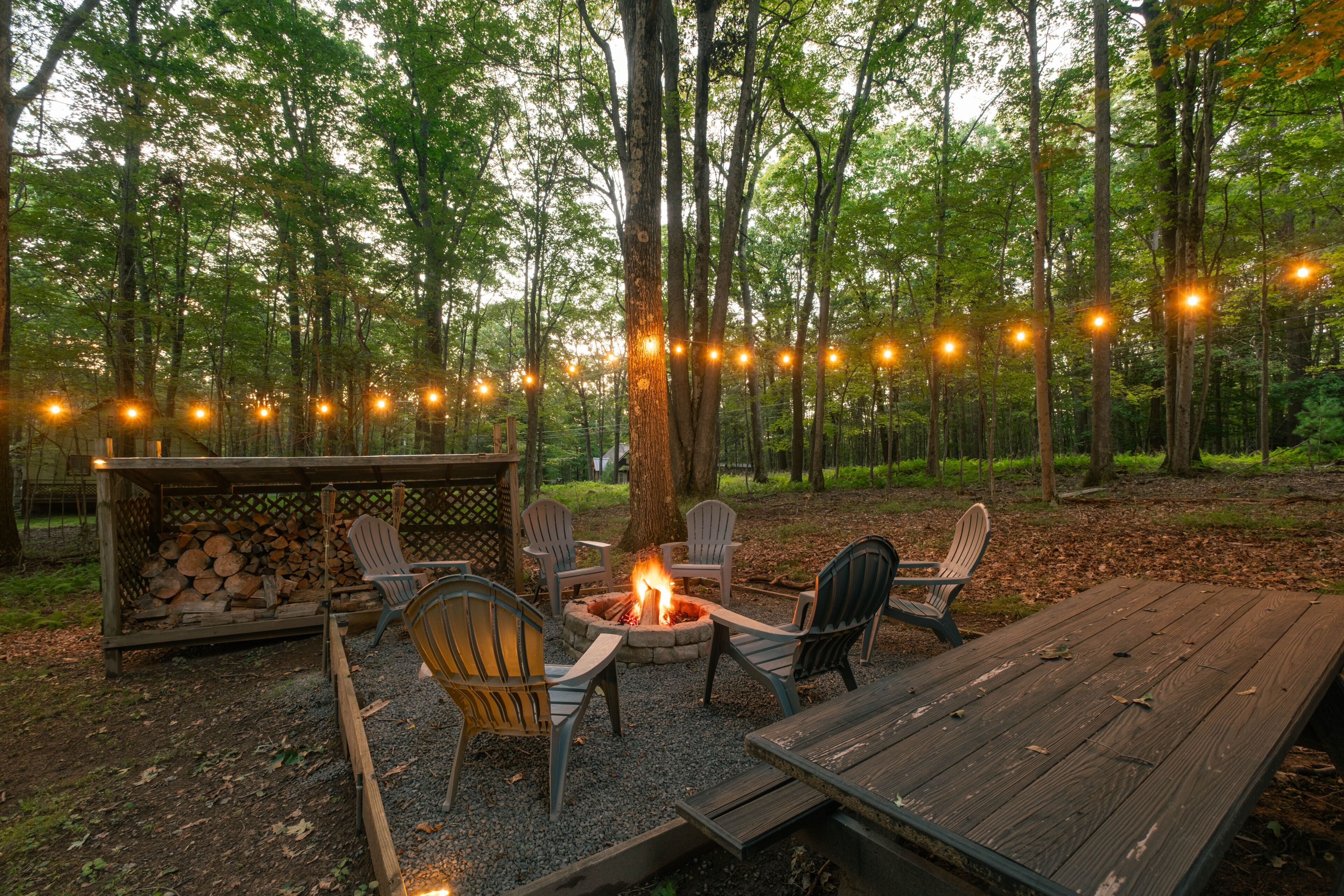 An outdoor seating area with a fire pit, chairs, and a wooden table.