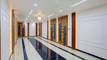 A long corridor with doors on one side and a reflective marble floor.