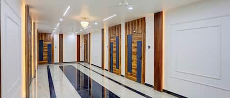 A long corridor with doors on one side and a reflective marble floor.