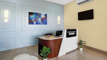 Ett välkomnande område med modern design, inklusive en receptionsdisk, en väggmonterad tv och en väggmonterad luftkonditioneringsanläggning.