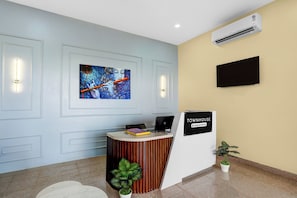 Un área de recepción con diseño moderno, que incluye un mostrador de recepción, un televisor montado en la pared y un equipo de aire acondicionado instalado.