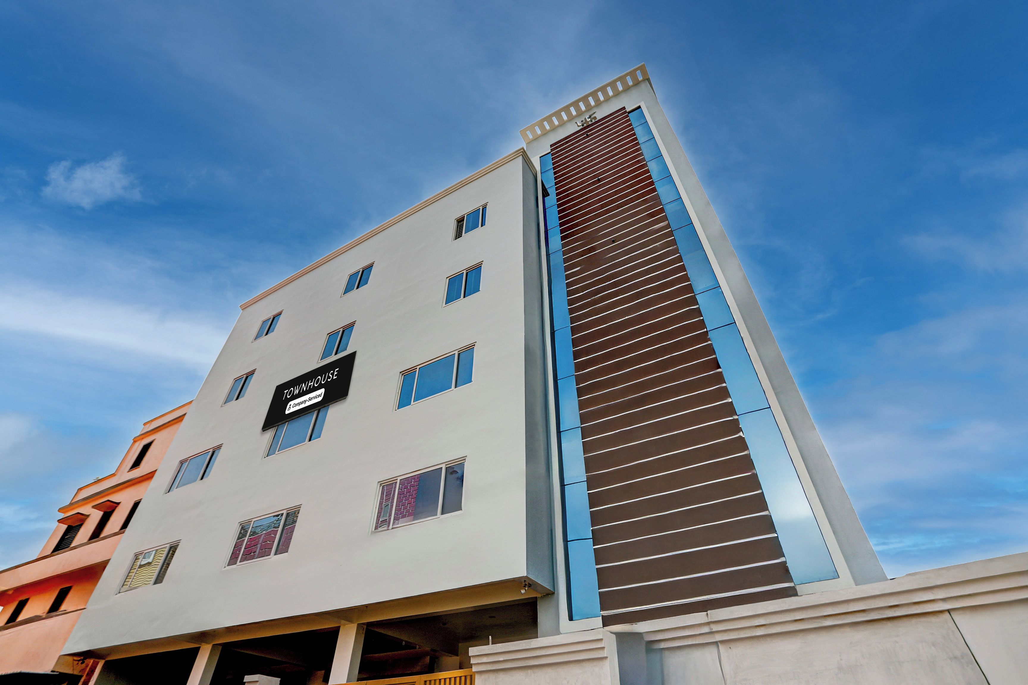 A multi-story building with a sign reading 'TOWNHOUSE' and 'Company Serviced'.