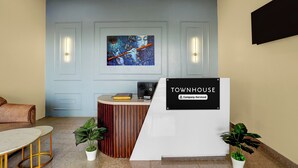 Ett välkomnande område med modern design, med en receptionsdisk, en sittgrupp med soffa och bord samt en stor, abstrakt målning på väggen.