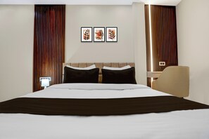 Una habitación de hotel con una cama grande, una mesita de noche, una silla y tres cuadros en la pared.