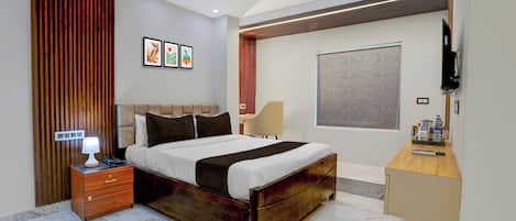 A modern bedroom with a bed, bedside table, lamp, and a flat-screen TV.