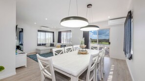 A modern living room with a dining area, large windows, and a view of the outdoors. - Shoreline Apartments - unit 13 (Bargara)